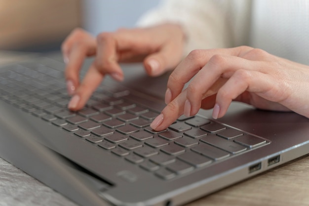 Foto gratuita primo piano della donna che scrive su un computer portatile