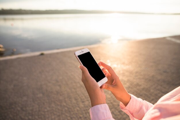 湖の前で携帯電話を使用して女性のクローズアップ