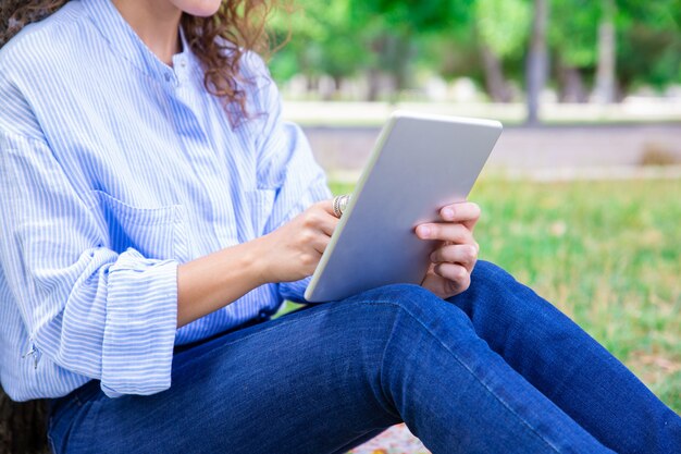 夏の公園でデジタルタブレットを使用して女性のクローズアップ