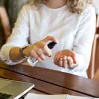 Free photo close-up woman using hand sanitizer