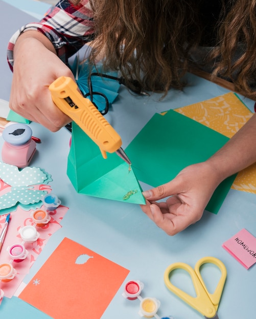 Close-up of woman using hot glue gun while making art craft