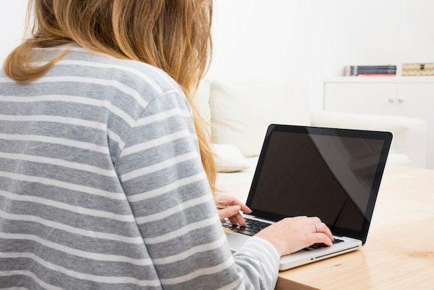 Foto gratuita primo piano della donna che per mezzo del computer portatile a casa