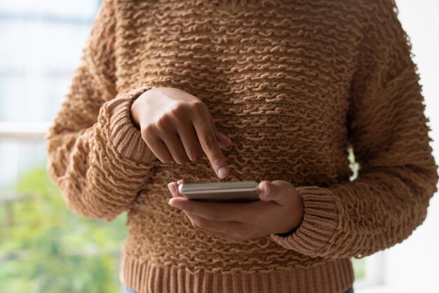 Close-up of woman using smartphone and scrolling web page