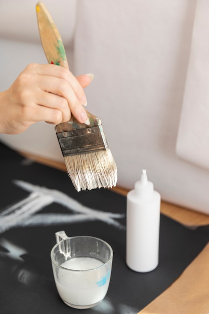 Close-up woman using white paint and brush