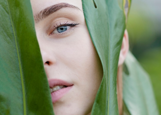 Close-up woman watching through leaves