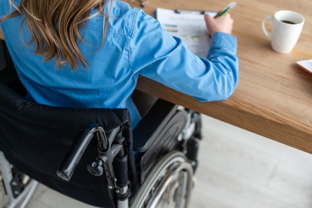 Close-up woman in wheelchair working at the office