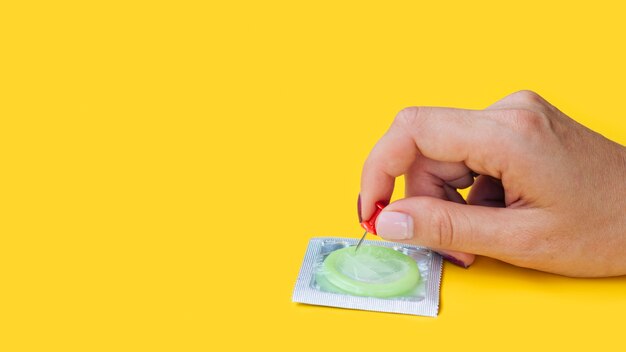 Close-up woman with condom holding a pin