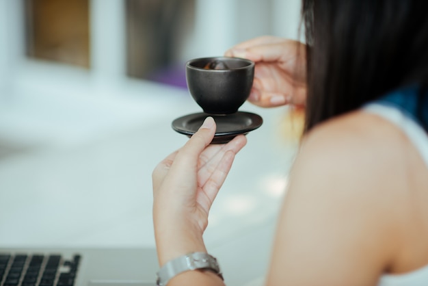 カフェでコーヒーカップを持つ女性を閉じる