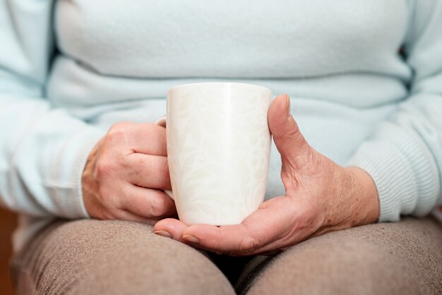 お茶のカップを持つクローズアップ女性