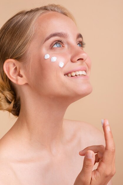 Close-up woman with face cream looking up