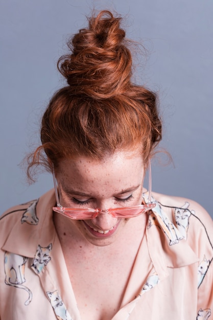 Close-up woman with hair bun and pink glasses