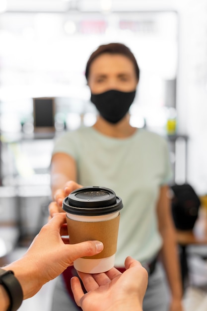 Close-up woman with mask buying coffee