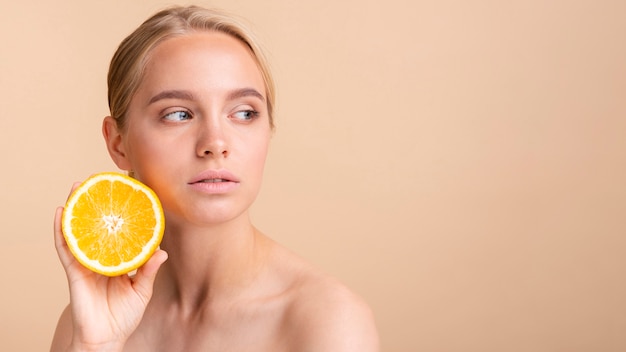 Close-up woman with orange looking away