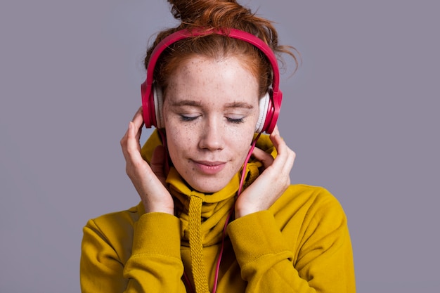 Close-up woman with red headphones and yellow hoodie