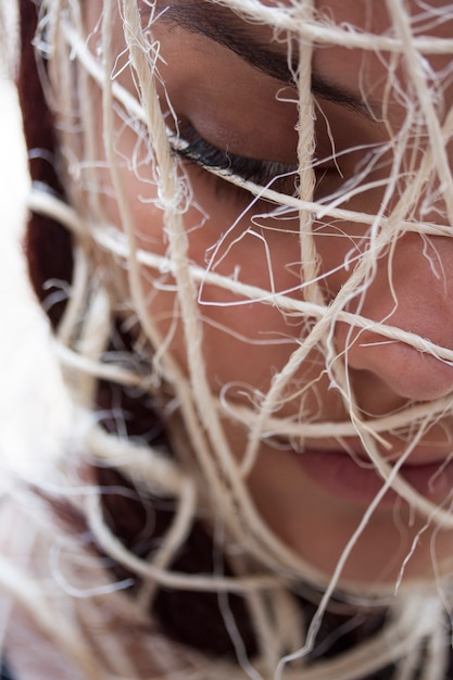 Close-up of woman with ropes around her head