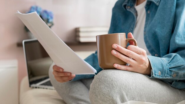 Close-up woman working on couch and drinking coffee