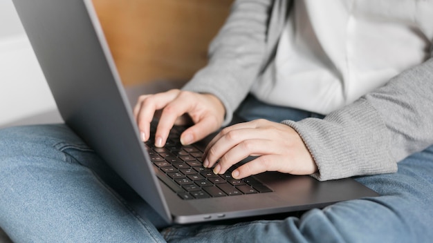 Close-up woman working on laptop in bed