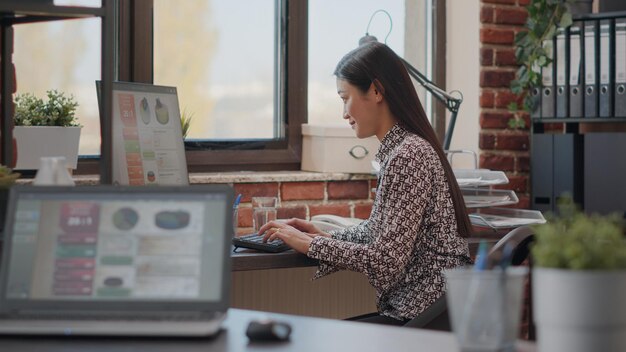コンピューターでプロジェクト計画に取り組んでいる女性のクローズアップ、オフィスでの開発のためのマーケティングと管理戦略を設計します。スタートアップビジネスの成長のために分析を使用している従業員。