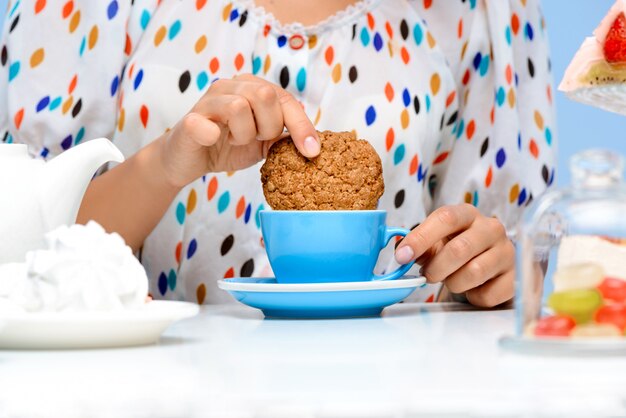 Close up of womans hands dipping cookie in milk