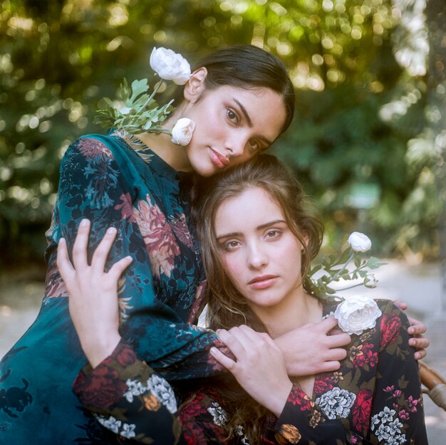 Close-up women in floral dresses holding each other