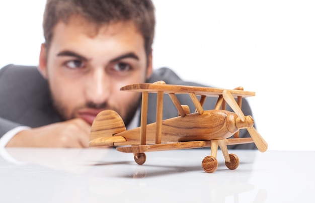 Close-up of wooden airplane with blurred businessman background