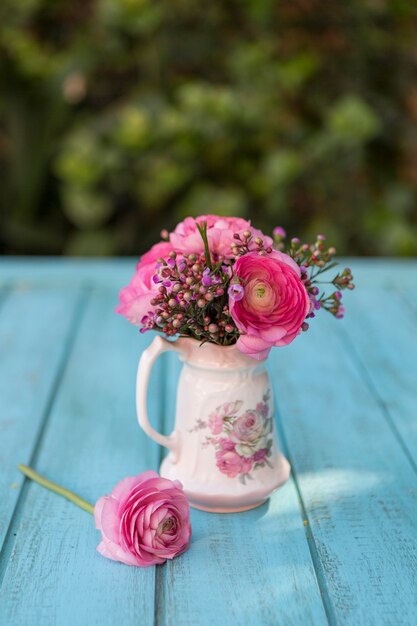 Close-up of wooden surface with vase and flowers