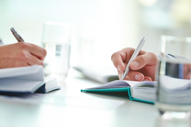 Close-up of workers writing with pen