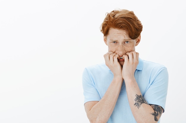 Free photo close-up of worried and insecure young redhead man biting fingernails, panicking