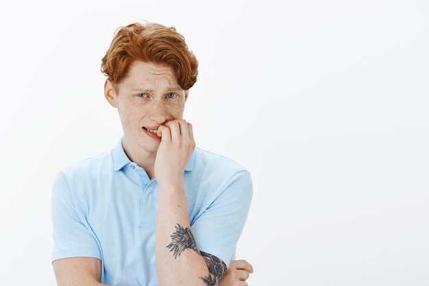 Free photo close-up of worried and insecure young redhead man biting fingernails, panicking