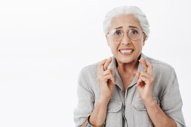 Free photo close-up of worried and nervous elderly woman in glasses cross fingers and praying