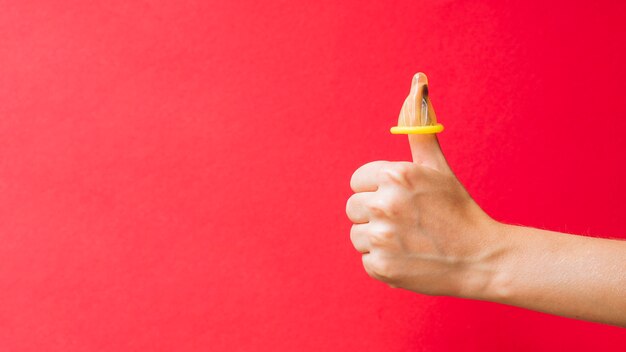 Close-up yellow condom on woman's finger 