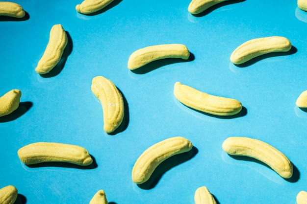 Close-up of yellow gummy banana candies on blue backdrop