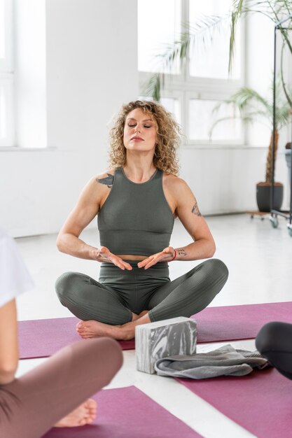 Close up yoga teacher leading practitioners