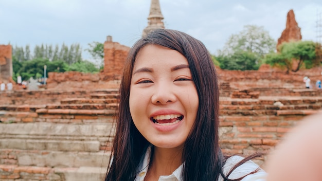 Close-up Young Asian backpacker blogger woman looks at front on smartphone