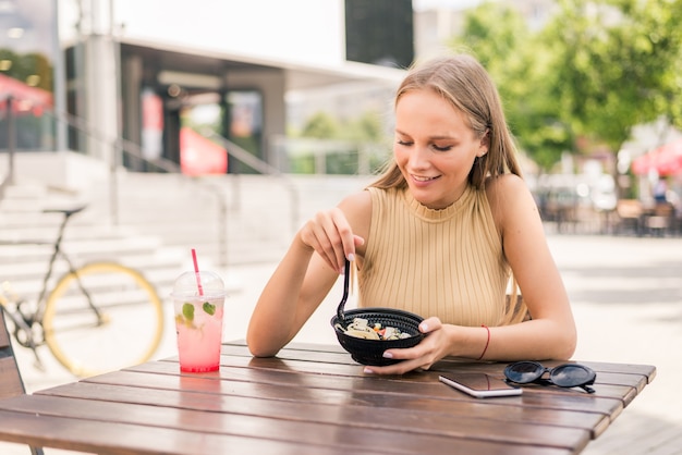 ストリートカフェでサラダを食べる若い魅力的な女性のクローズアップ