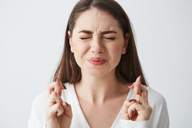 Close up of young beautiful businesswoman praying with closed eyes .