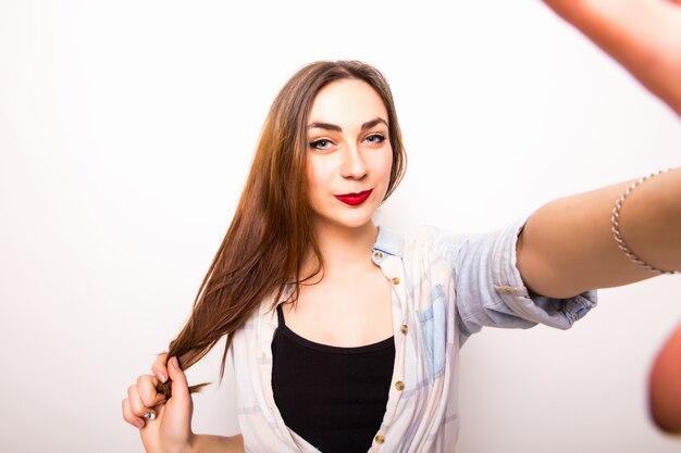 Close-up of young beautiful woman taking selfie. Isolated white