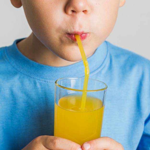 Free photo close-up young boy drinking juice