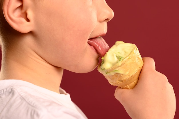 Foto gratuita giovane ragazzo del primo piano che mangia il gelato saporito