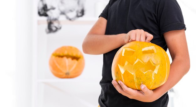 Close-up young boy holding carved pumpkin