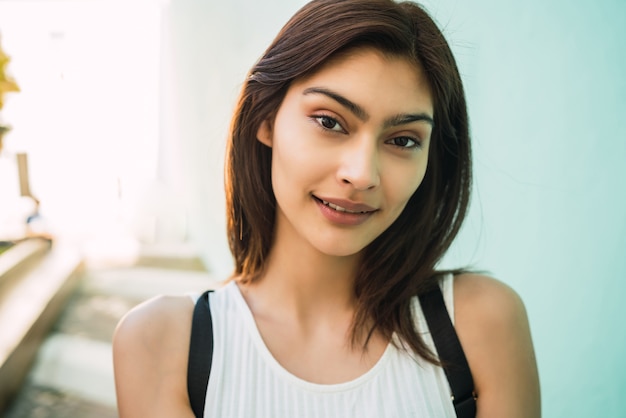 Close-up of young brunette latin woman smiling outdoors in the street. Urban concept.