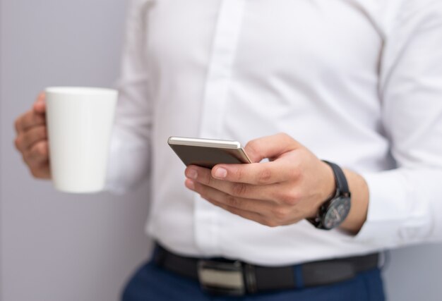 Close-up of young businessman using mobile phone indoors