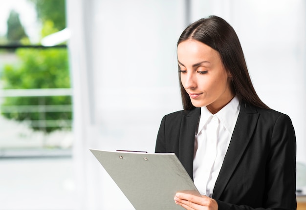Close-up of young businesswoman looking at clipboard