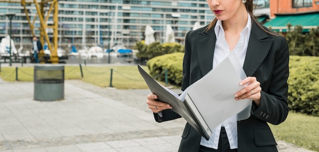 Free photo close-up of a young businesswoman reading folder at outdoors