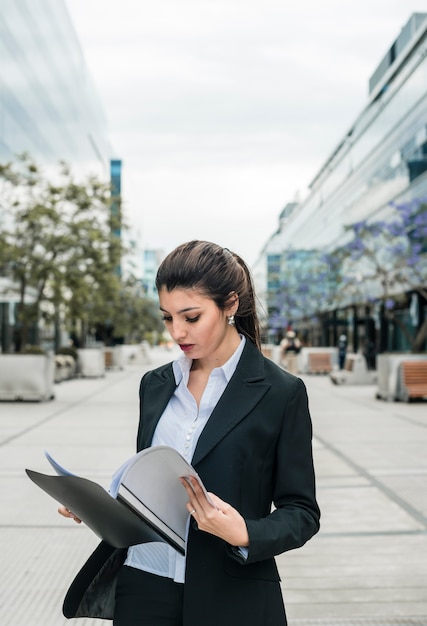 Free photo close-up of a young businesswoman reading the folder at outdoors