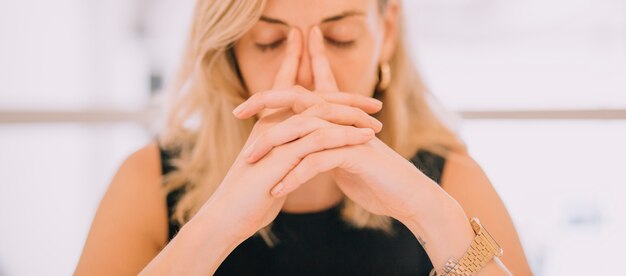 Close-up of young businesswoman with hands over face