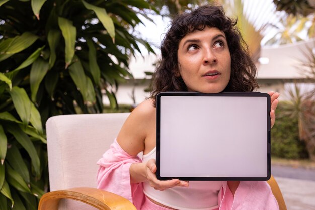 Close up of young caucasian brunette woman holding blank digital tablet mockup outdoors Technology concept