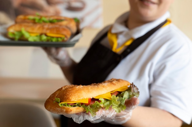 Free photo close up on young chef holding sandwiches