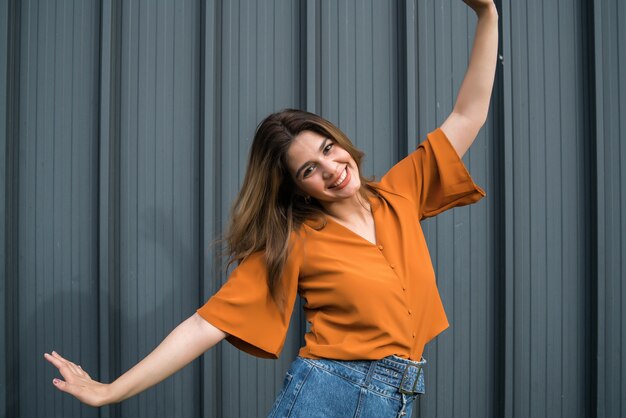 Close-up of young confident woman smiling and celebrating while standing outdoors on the street. Urban concept.