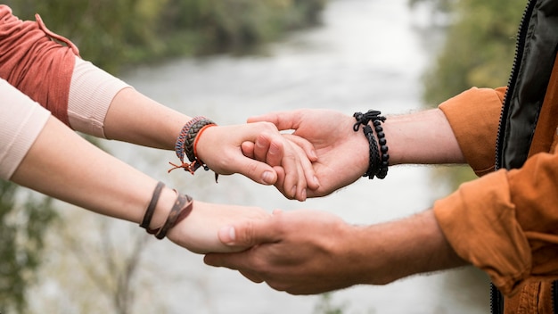 Free photo close-up young couple holding hands near river